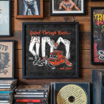Lade das Bild in den Galerie-Viewer, a framed poster with the text "United Through Music..." and illustrations of a person wearing jeans and shoes, along with the text "and Beer!" The poster is displayed on a wall among various other framed items, such as photographs and CDs.
