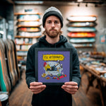 Cargar imagen en el visor de la galería, A man holding a framed poster with a cartoon illustration of a person sitting on a couch with a skateboard in their hand.
