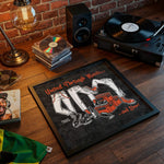 Lade das Bild in den Galerie-Viewer, a framed poster with an illustration of a pair of legs wearing sneakers, along with the text "United Through Music... and Beer" and "Original Clothing". The poster is placed on a wooden surface, surrounded by various items such as a record player, a lamp, and a stack of CDs.
