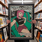 Load image into Gallery viewer, A person is holding up a framed poster featuring a pop art style illustration of a woman with pink hair and a black and white checkered shirt. The poster has a title that reads "She's a BOMBSHELL" and includes text that reads "CRACKED TOOTH" and "BEEN SIX MONTHS BUT I'LL NEVER BE THE SAME. NOBODY REMEMBER HER. SHE'S A BOMBSHELL."
