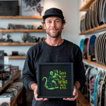 Load image into Gallery viewer, A man is holding a framed picture with a cartoon rat on it, standing in a room with shelves of skateboards in the background.
