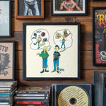Lade das Bild in den Galerie-Viewer, a framed cartoon illustration of two people, one with a tattoo, on a wall with various framed pictures and CDs below it.
