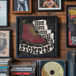 Load image into Gallery viewer, a framed poster with a bold statement about boots, "These boots were made for stomping", surrounded by various framed images and CDs on a wooden wall.
