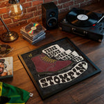 Load image into Gallery viewer, a framed poster with a graphic of a red boot and the text "These boots were made for stompin'". The poster is placed on a wooden surface, surrounded by various items such as a record player, a lamp, and a stack of CDs.

