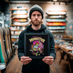 Load image into Gallery viewer, A man holding a framed poster with a cartoon-style illustration of a monster.
